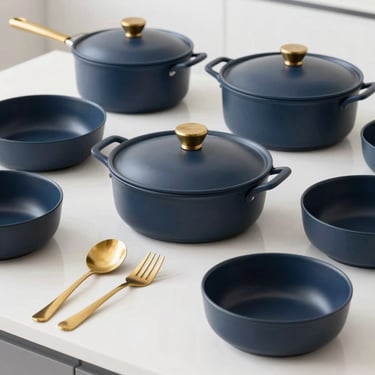 High-end matte ceramic cookware and brass utensils arranged neatly on a clean white countertop.