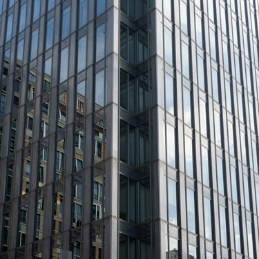 Detail of a clean glass and steel office facade reflecting bright daylight, symmetrical framing