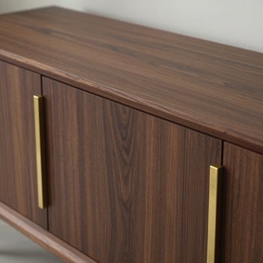 Sleek minimalist custom credenza in dark walnut, showcasing precise joinery and brass hardware details
