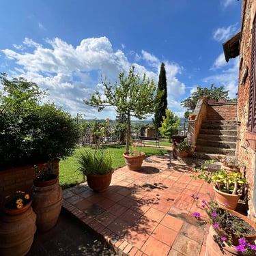Charming Tuscan garden terrace with cotto tiles, potted plants, and scenic countryside views in Certaldo Alto