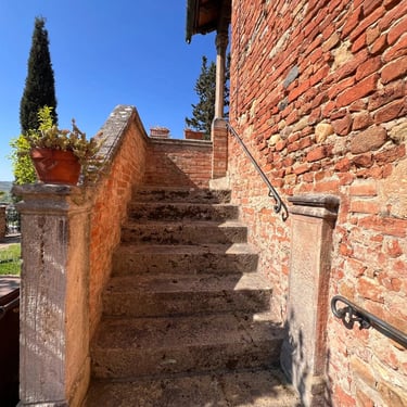 Historic stone staircase with iron railing and brickwork in a traditional property in Certaldo Alto, Tuscany