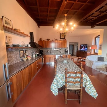 Wide-angle interior shot of a spacious Tuscan kitchen and dining room with a traditional coffered wood ceiling