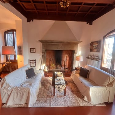 Historic Tuscan living room with stone fireplace, coffered ceiling, and terracotta floors in Certaldo Alto home