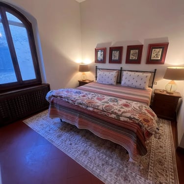 Charming historic bedroom with terracotta floors, iron bed, and traditional decor in Certaldo Alto, Tuscany