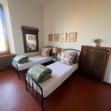 Cozy twin bedroom with iron bed frames and traditional Tuscan decor in a historic Certaldo Alto home
