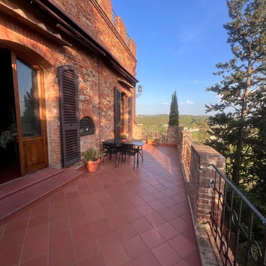Charming terracotta terrace at a historic brick home in Certaldo Alto, Tuscany, with scenic countryside views