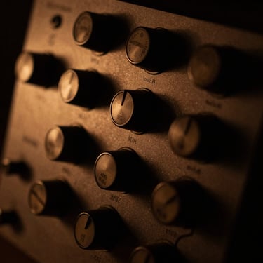 Macro shot of vintage analog compressor dials, warm amber light, dark shadows, technical precision