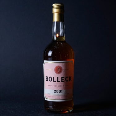 A beautiful sealed glass bottle containing a dark amber liquor, elegant vintage label, warm candlelight glow, moody dark background