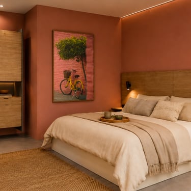 Modern bedroom with terracotta walls, wooden headboard, and minimalist desk area.