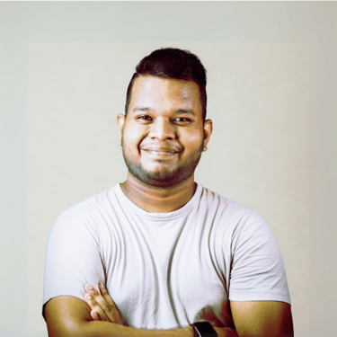 Smiling man with folded arms wearing a light shirt in front of a neutral background
