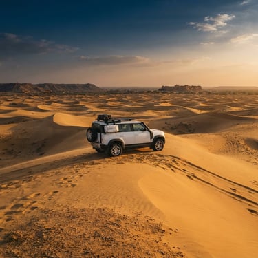 A premium white SUV parked on the crest of a golden sand dune in Jaisalmer during golden hour, majestic scale, warm light