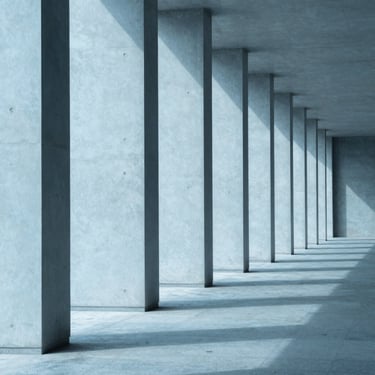 A series of clean, modern concrete pillars casting long, structured shadows, architectural symmetry.