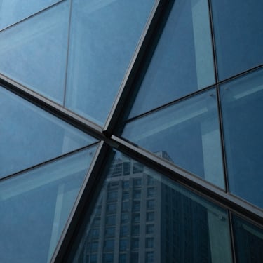 Abstract architectural detail of intersecting glass planes, deep blue tones, clean lines.