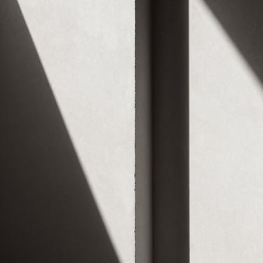 Extreme close-up of abstract architectural shadows on a white concrete wall, high contrast black and white, sepia undertones