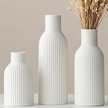 Three white ribbed ceramic vases in different sizes with dried flowers for minimalist home decor.
