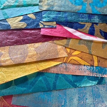 Stack of colorful hand-painted collage papers with layered patterns