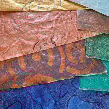 Stack of collage papers in blue, copper, and teal tones