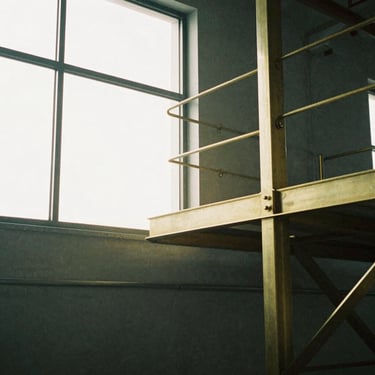 Tight abstract architectural detail of a manufacturing facility, soft natural window light, muted slate tone, 35mm