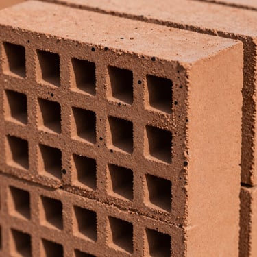 Macro shot of high-density engineering clay brick, showing dark vitrified spots and heavy structural mass.