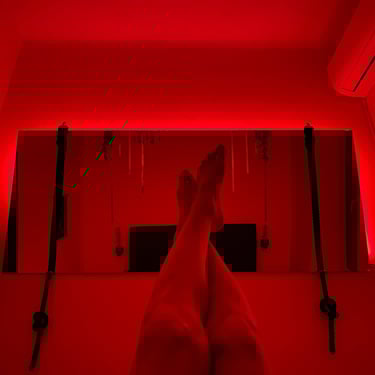 The photo shows legs in front of bedroom mirror, with red mood lights turned on behind the mirror.
