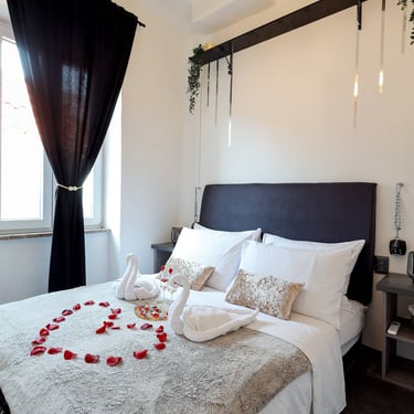 The photo shows the bedroom in Pleasure Palace - BDSM Love Apartment. Bed decorations are towel swans and rose petals heart.