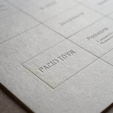 Extreme close-up of custom embossed brand guidelines on heavy cotton paper stock, cool Pacific Northwest light, geometric alignment.