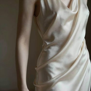 An elegant, abstract composition showing a silk fabric draped gracefully over a sculptural form, with soft lighting emphasizing smooth contours and refined shapes.