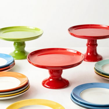 A collection of colorful ceramic cake stands and dessert plates arranged on a table, high-key commercial photography