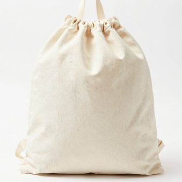 Bright high-key product photo of a cotton drawstring backpack, soft natural daylight, 50mm