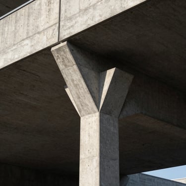 Architectural detail of a modern concrete and steel building foundation, dramatic side-lighting, sharp angles.