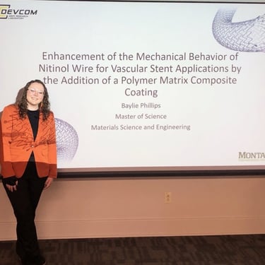 Baylie Phillips standing in front of a projector screen for her Master of Science defense project.