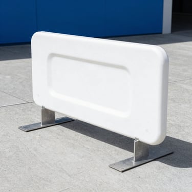Crisp eye-level commercial shot of a pedestrian barrier with flat steel feet deployed on a clean Auckland concrete pavement, bright natural daylight, 35mm lens