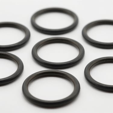 Close-up macro shot of industrial rubber gaskets and O-rings, clean edges, neutral light gray background, 50mm lens.