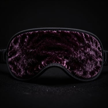 Dramatic low-key studio detail shot of a velvet blindfold, chiaroscuro lighting, deep shadows, rich dark tones.