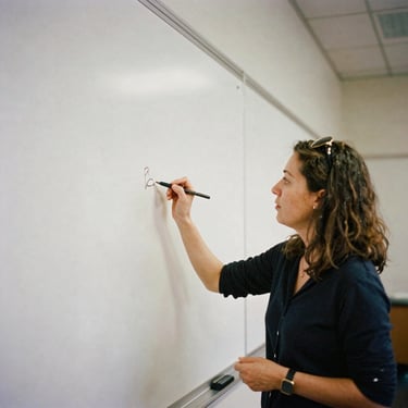 Candid portrait of a female educator writing on a whiteboard during a local workshop, soft daylight, natural tones, warm documentary style, 35mm film grain