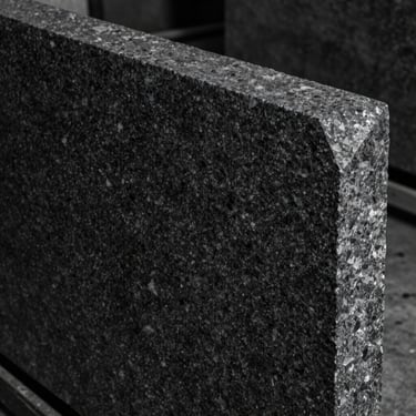 Slab of dark absolute granite, fine grain texture, deep charcoal tone, water-cut precise edge, high contrast