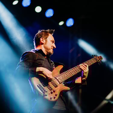 A lively band performing on stage with vibrant lighting in a night setting.