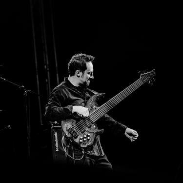 A striking black and white image of Jozef Bobula onstage playing bass during a live concert.