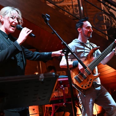 Female vocalist singing with Jozef Bobula on bass performing live on stage in an intimate warmly lit venue.