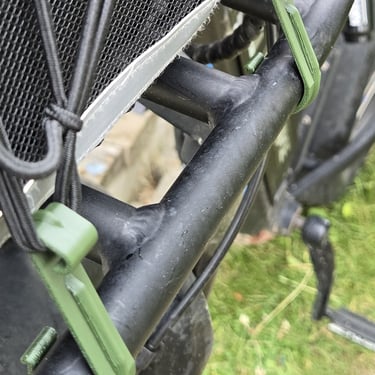 Close-up of green clips on a black bicycle frame.