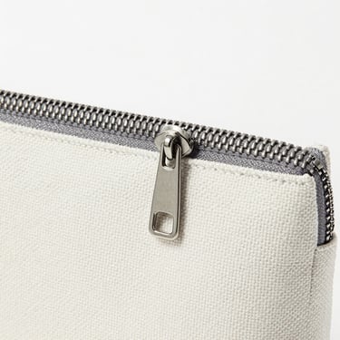 Close-up of a premium metal zipper on a custom canvas pouch, clean alignment, studio lighting