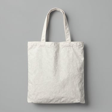Minimalist canvas tote bag with thick texture, clean stitching details, centered flat-lay on a cool gray background