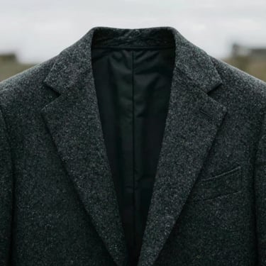 A close-up of a well-fitted charcoal wool suit jacket collar, minimalist style