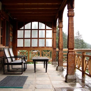 Manali trip details - A tranquil wooden balcony at Naggar Castle overlooking a misty Himalayan valley