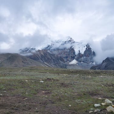 North East trip details - A soulful view of snow-capped Himalayan peaks partially hidden by thick white clouds.