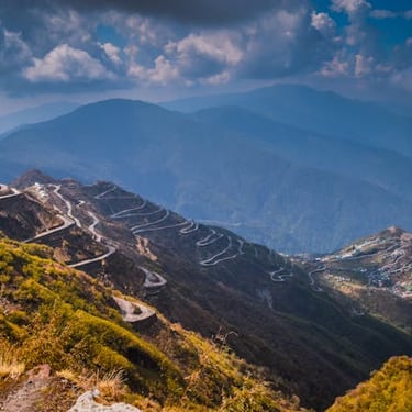 North East trip details - Aerial view of a winding zig-zag road through the steep, misty hills of East Sikkim.