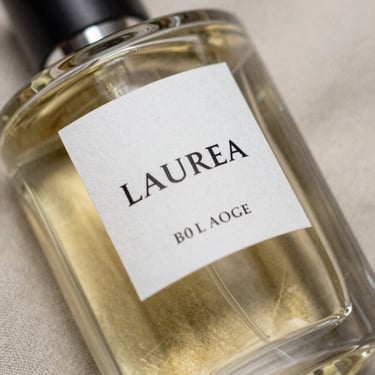 Close-up of a luxury perfume bottle made of heavy glass, resting on a raw linen cloth with elegant serif typography on the label.