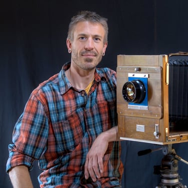 jeune blond posant en souriant accoudé à sa chambre photographique