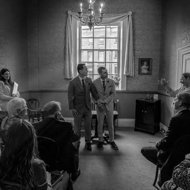 two grooms listening to their friend give a speech at their ceremony