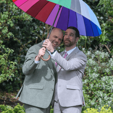 two grooms under their rainbow umbrella